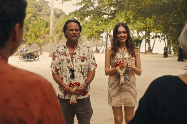 a couple standing with floral offerings outdoors during a ceremony