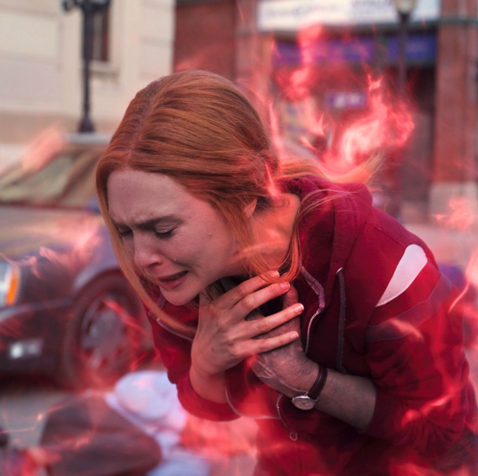 wanda is upset, clutching her hands to her neck as she cries and her red magic is surrounding her in wandavision epiosde 9