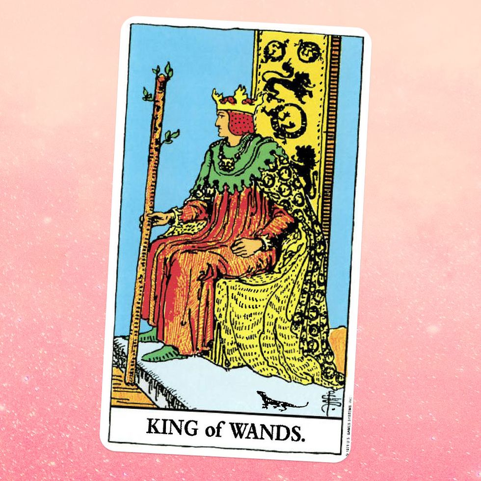 the tarot card the king of wands, showing a king in a robe and crown sitting on a throne and holding up a large wooden staff