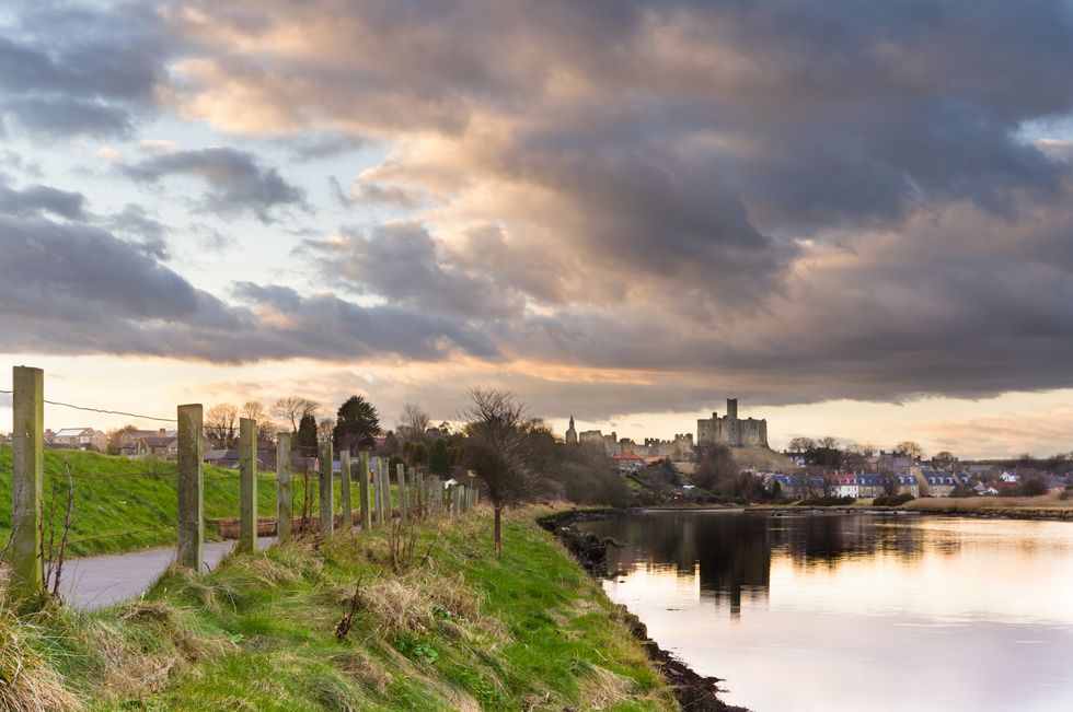 atmospheric sky reflecting warkworth castle in the river coquet