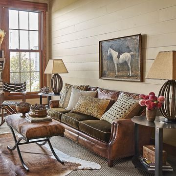 rustic living room with layered textures, warm rich cream colored walls, natural wood trim, brick fireplace