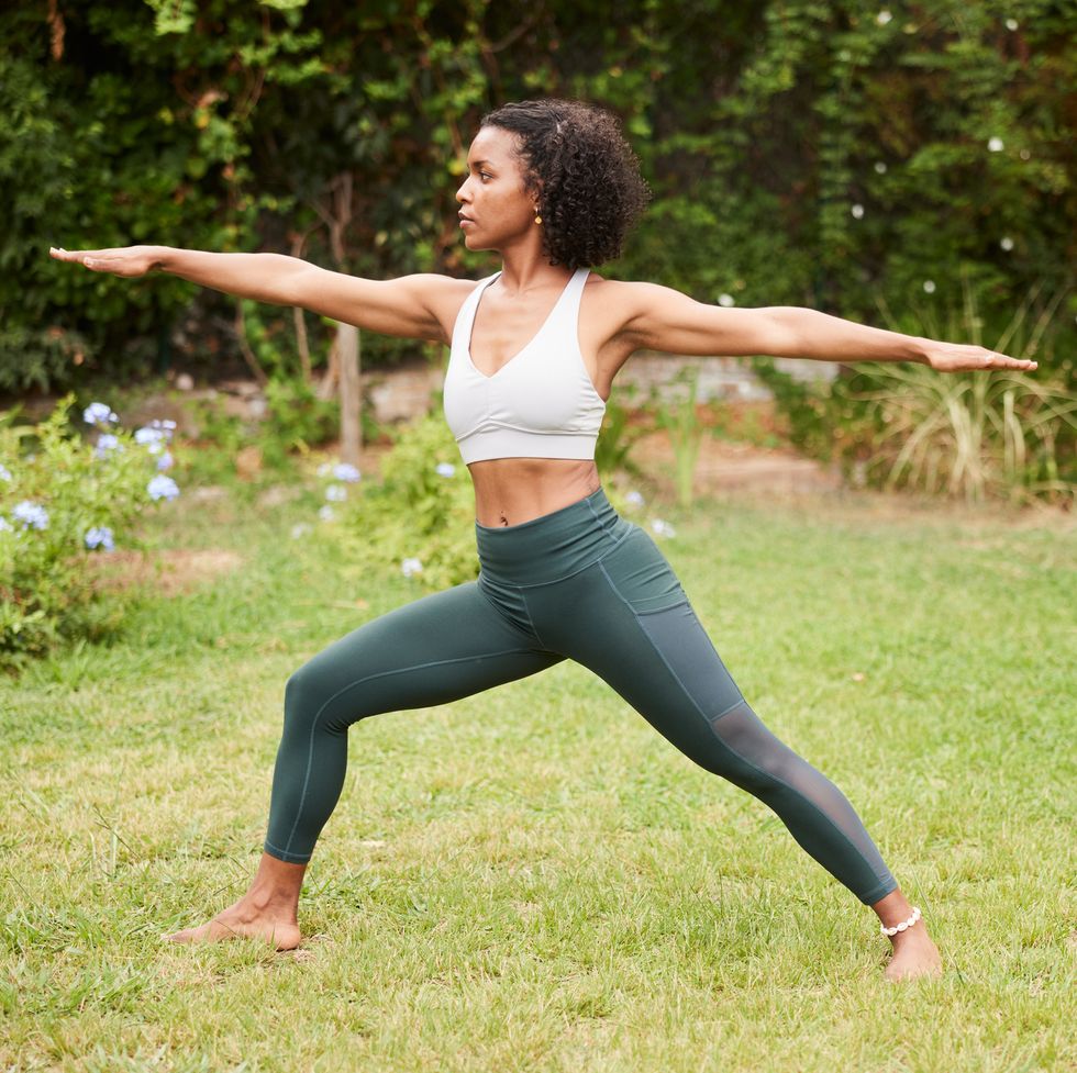 warrior two pose, also known as virabhadrasana ii, with a female yoga instructor in garden
