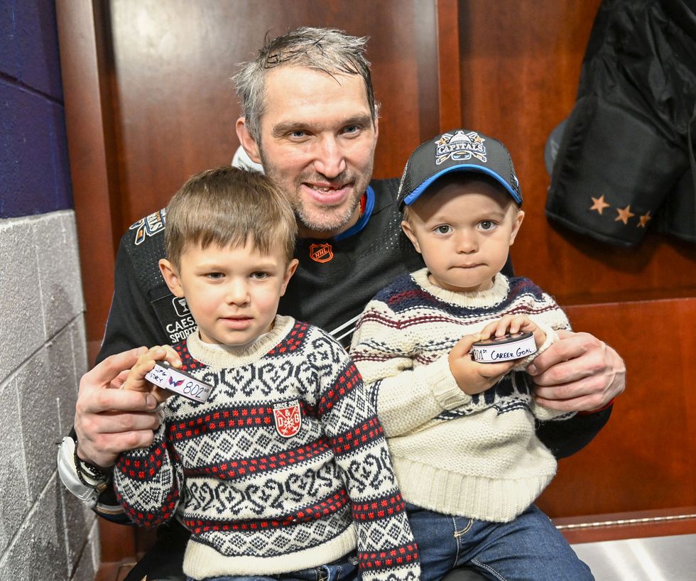 alex ovechkin hugging his sons while sitting in his locker stall