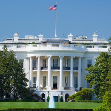 USA, Washington DC, the White House, close-up view of the white house on a bright sunny day, a fountain and green lawn are visible before the white building which has an american flag waving in the wind on top