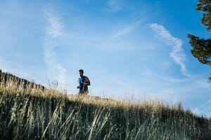 man jogging in field against blue sky