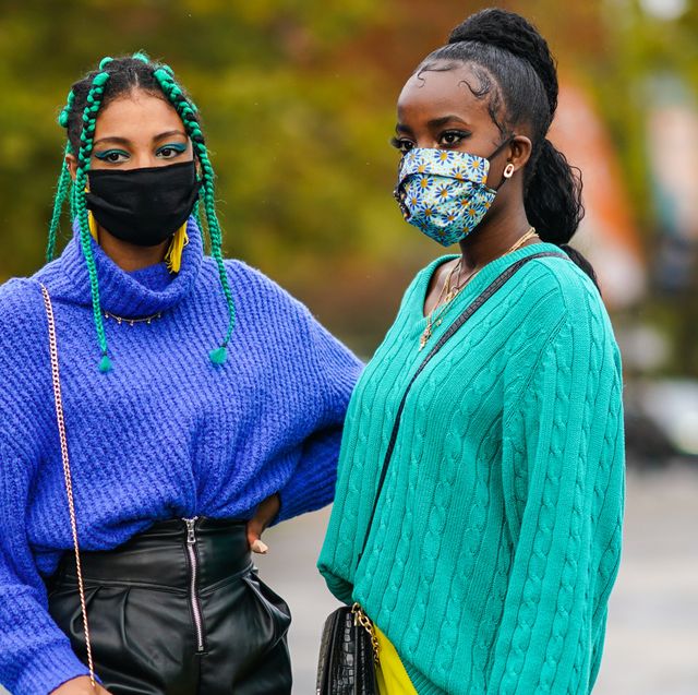 twee zwarte vrouwen in kleurrijke truien met mondkapjes poseren voor camera tijdens paris fashion week in oktober 2020