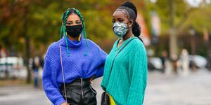 twee zwarte vrouwen in kleurrijke truien met mondkapjes poseren voor camera tijdens paris fashion week in oktober 2020