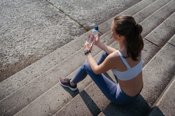 een vrouw zit na het hardlopen met een flesje water