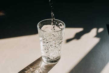 water being poured in a glass of water that cast a beautiful shadow on a white kitchen countertop