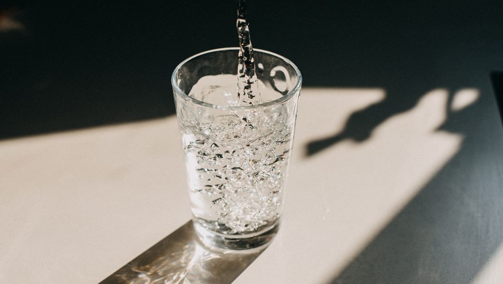 water being poured in a glass of water that cast a beautiful shadow on a white kitchen countertop
