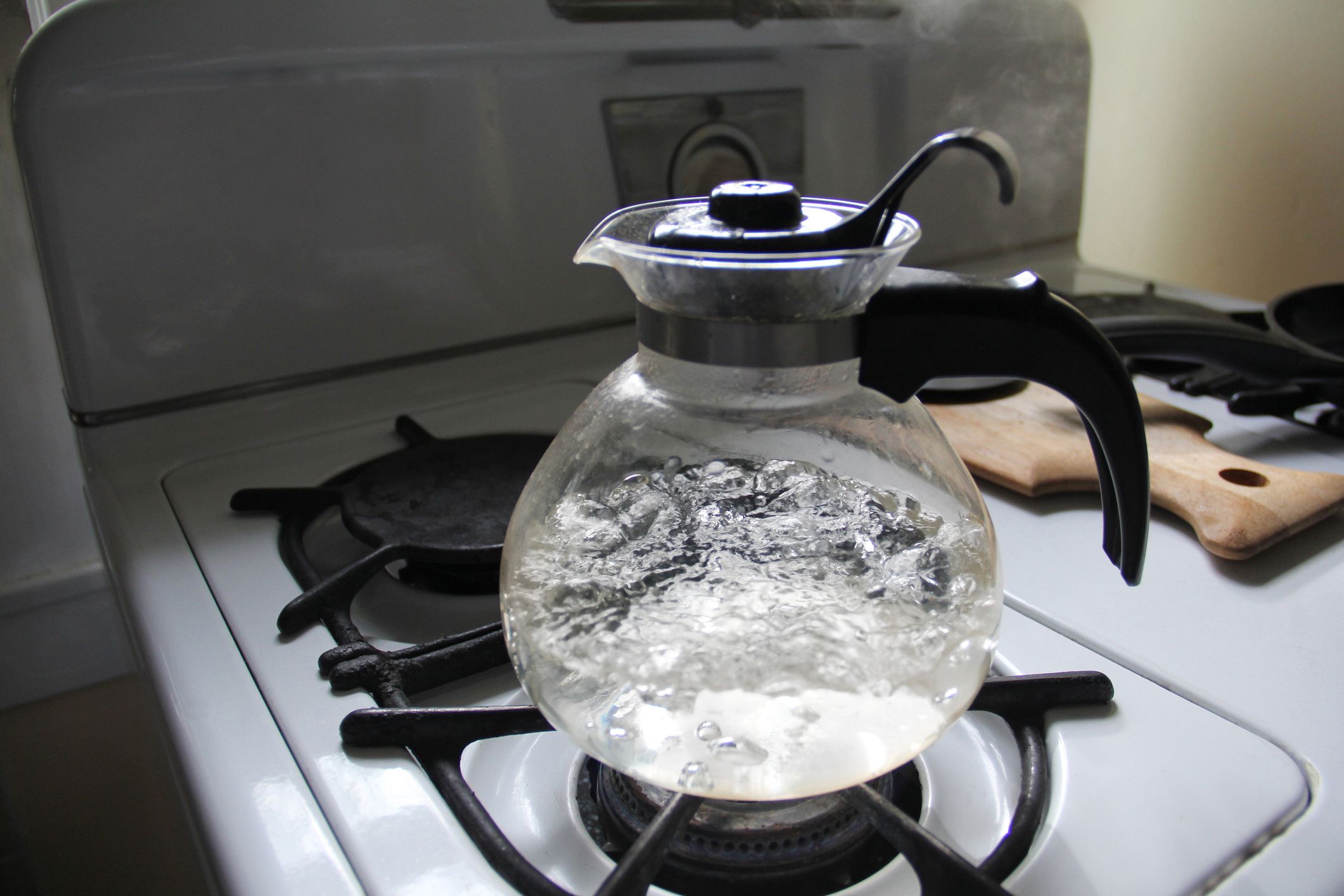 Red tea drink is boiled in a glass kettle on a gas stove, close-up