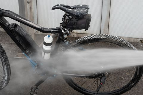 water spraying on bicycle outdoors   drivetrain wash
