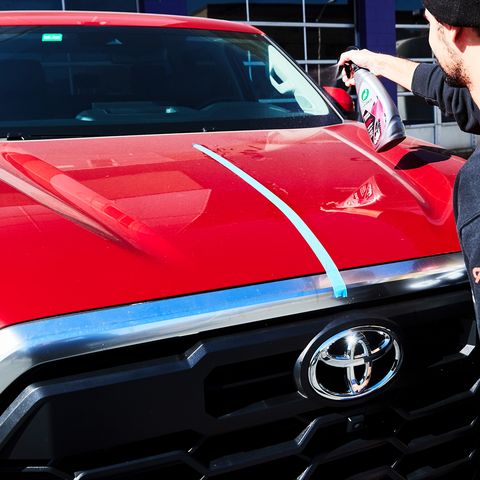 Spraying 3-in-1 waterless turtlewax laundry detergent on the hood of a red truck