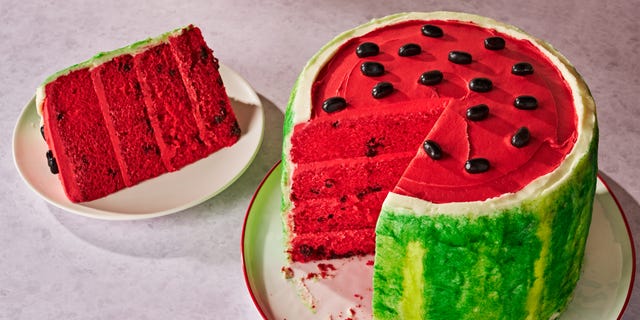 cake colored and decorated to look like a watermelon, with green stipple frosting on the outside, red frosting for the top, and black jelly beans for the seeds
