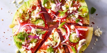 watermelon slices topped with red onion, sliced cucumbers, feta, and mint