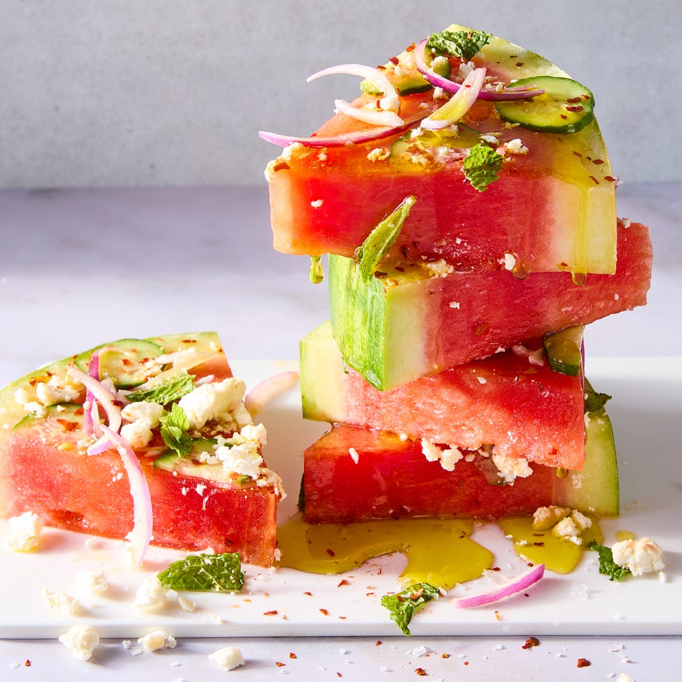 watermelon slices topped with red onion, sliced cucumbers, feta, and mint
