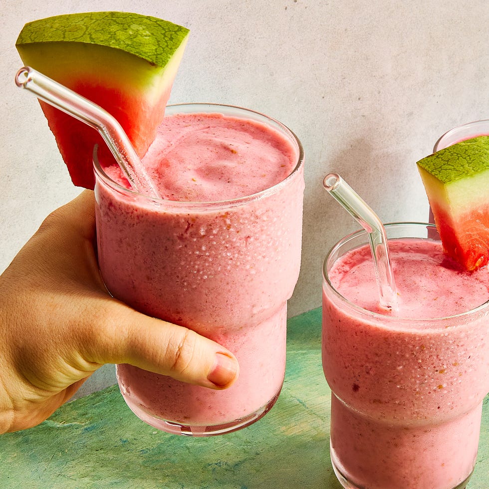 watermelon smoothie in a glass with a straw and a watermelon garnish