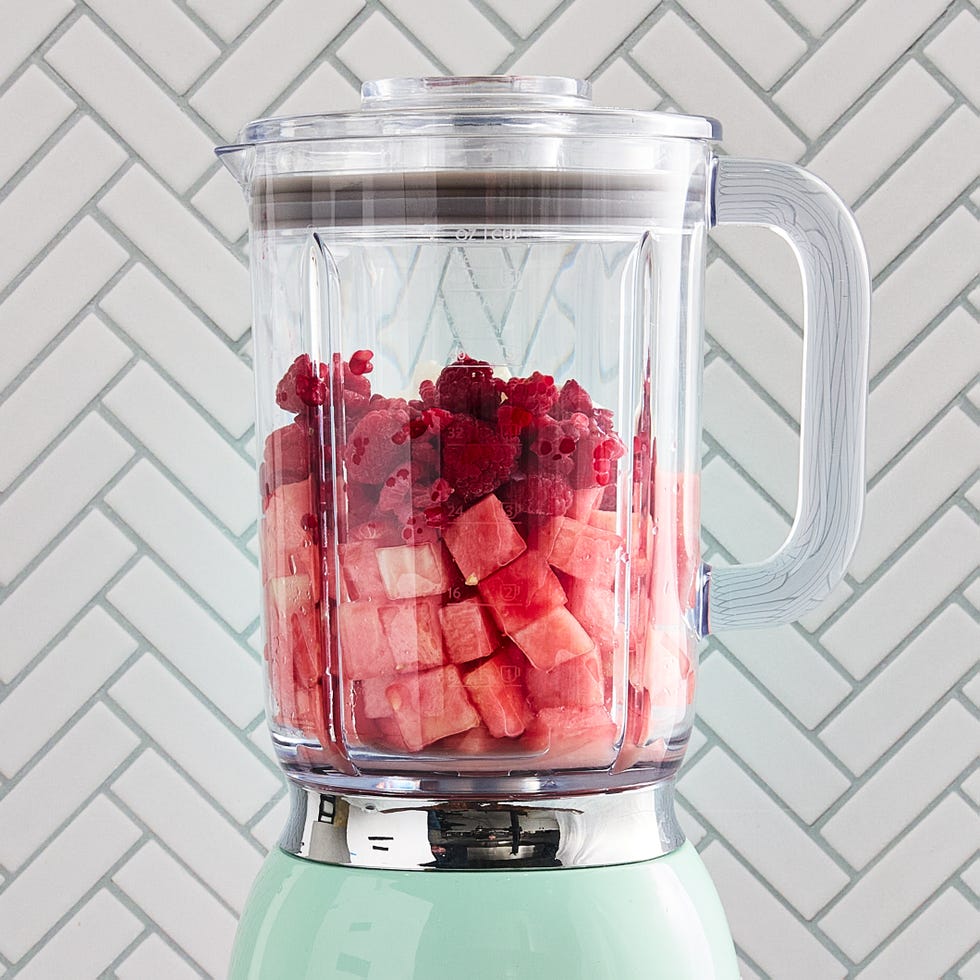 watermelon smoothie in a glass with a straw and a watermelon garnish