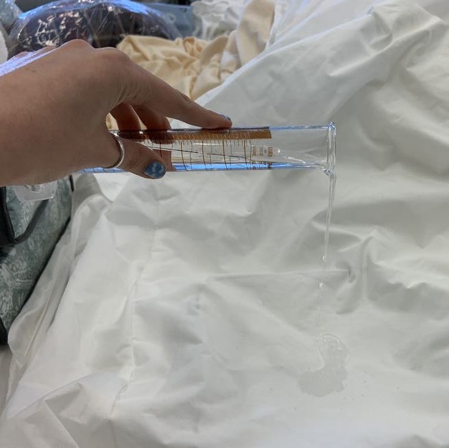 best mattress protectors - waterproof testing a lab analyst pouring a set amount of distilled water onto a mattress protector to evaluate its waterproof abilities
