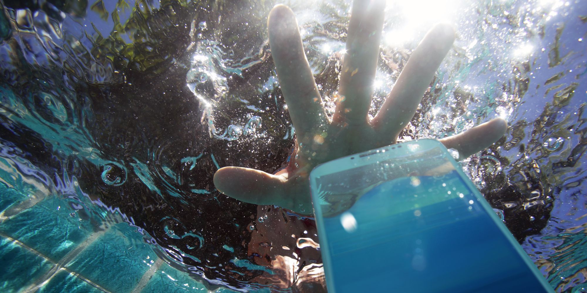 hand reaching for phone dropped in pool