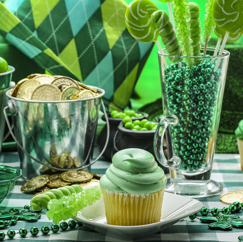 st patricks day activities table with green cupcakes, cookies, cups, and necklaces