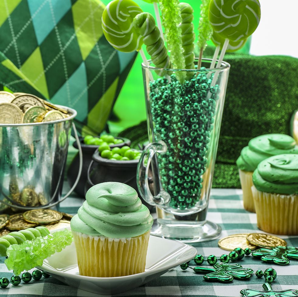 st patricks day activities table with green cupcakes, cookies, cups, and necklaces