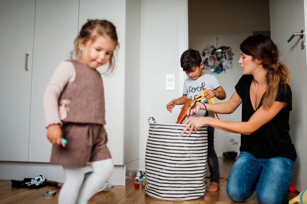 una madres con dos niños recogiendo los juguetes
