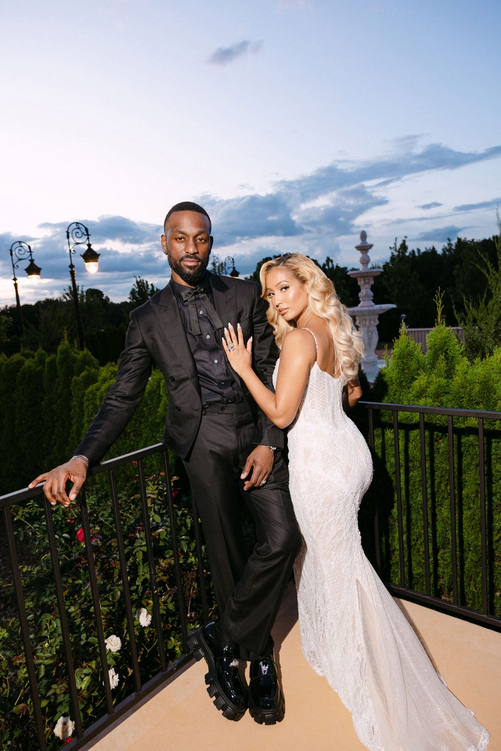 a bride and groom lean against a railing