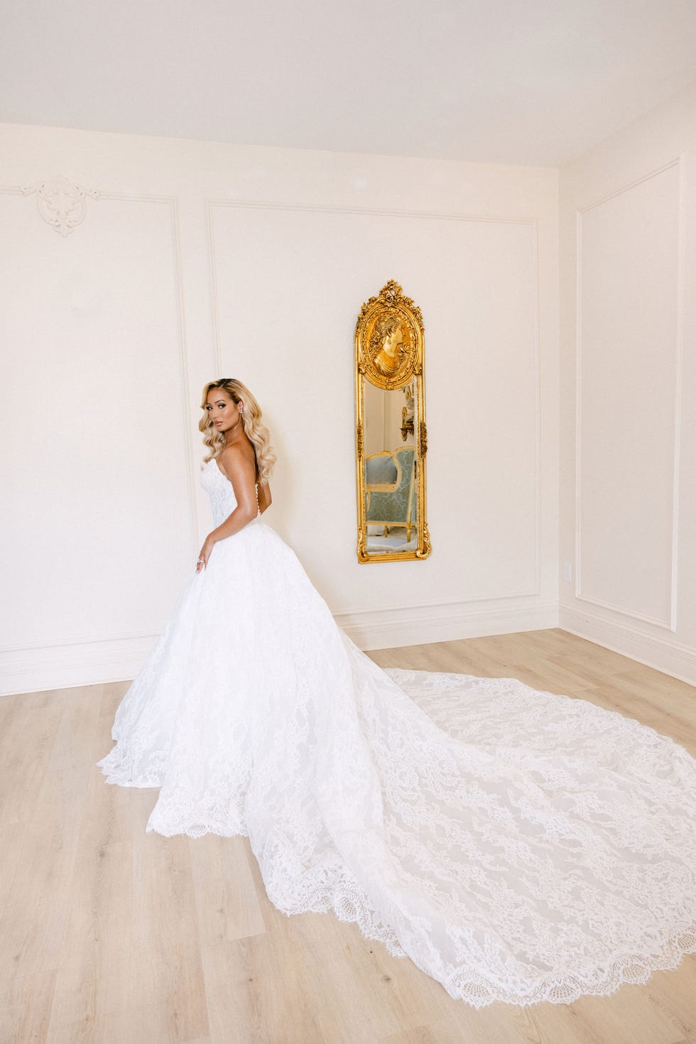 bride in a white wedding gown with a long train standing in a decorated room