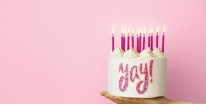 birthday captions for instagram hand holding birthday cake with pink candles and yay written in sprinkles