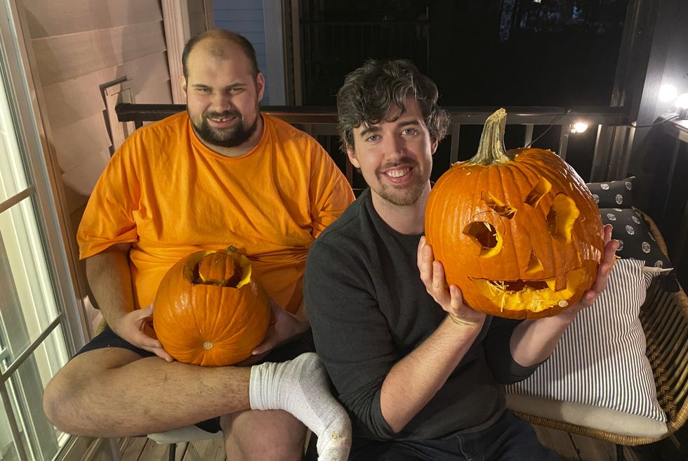 alex and tony show off their carved pumpkins on the porch