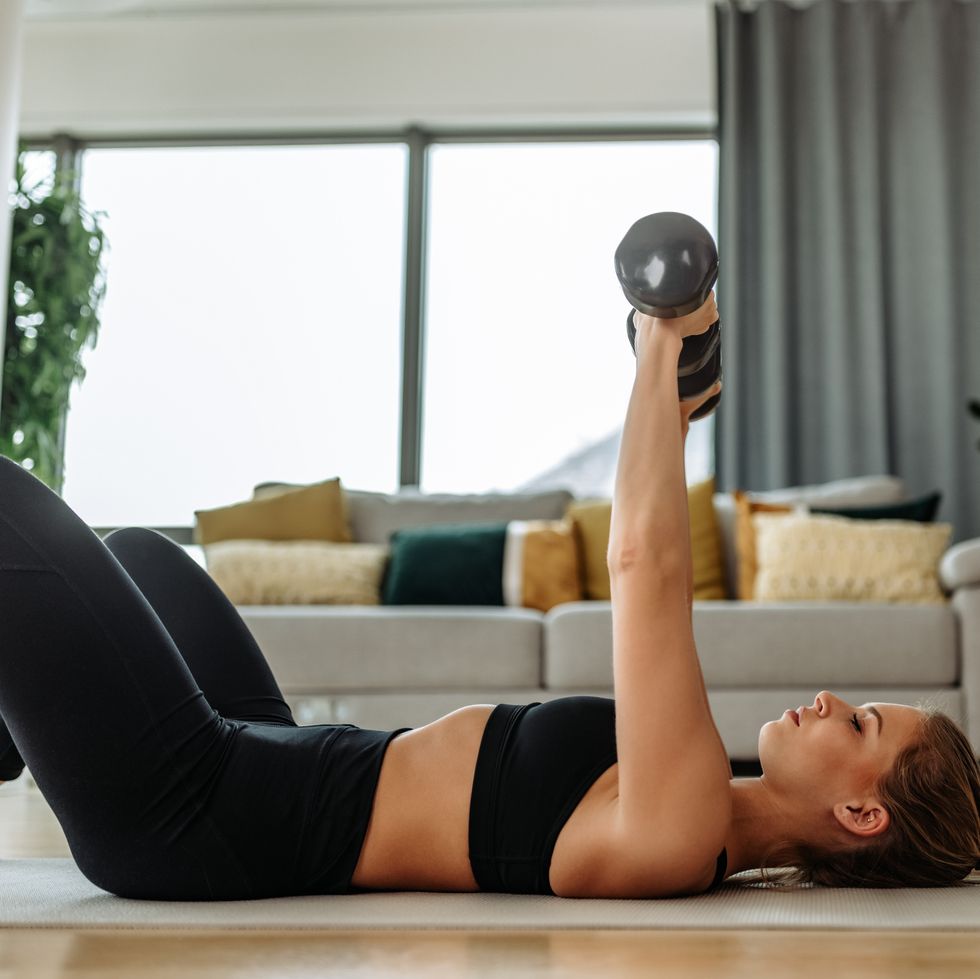 wearing sports bra and leggings, exercising with dumbbells