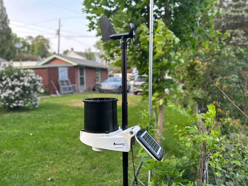 a weather station on a tripod in a yard