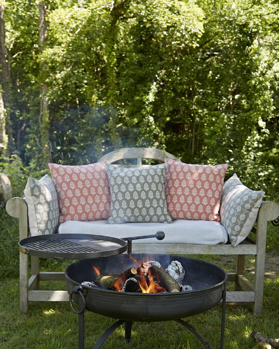 a grill with a fire pit and pillows on it