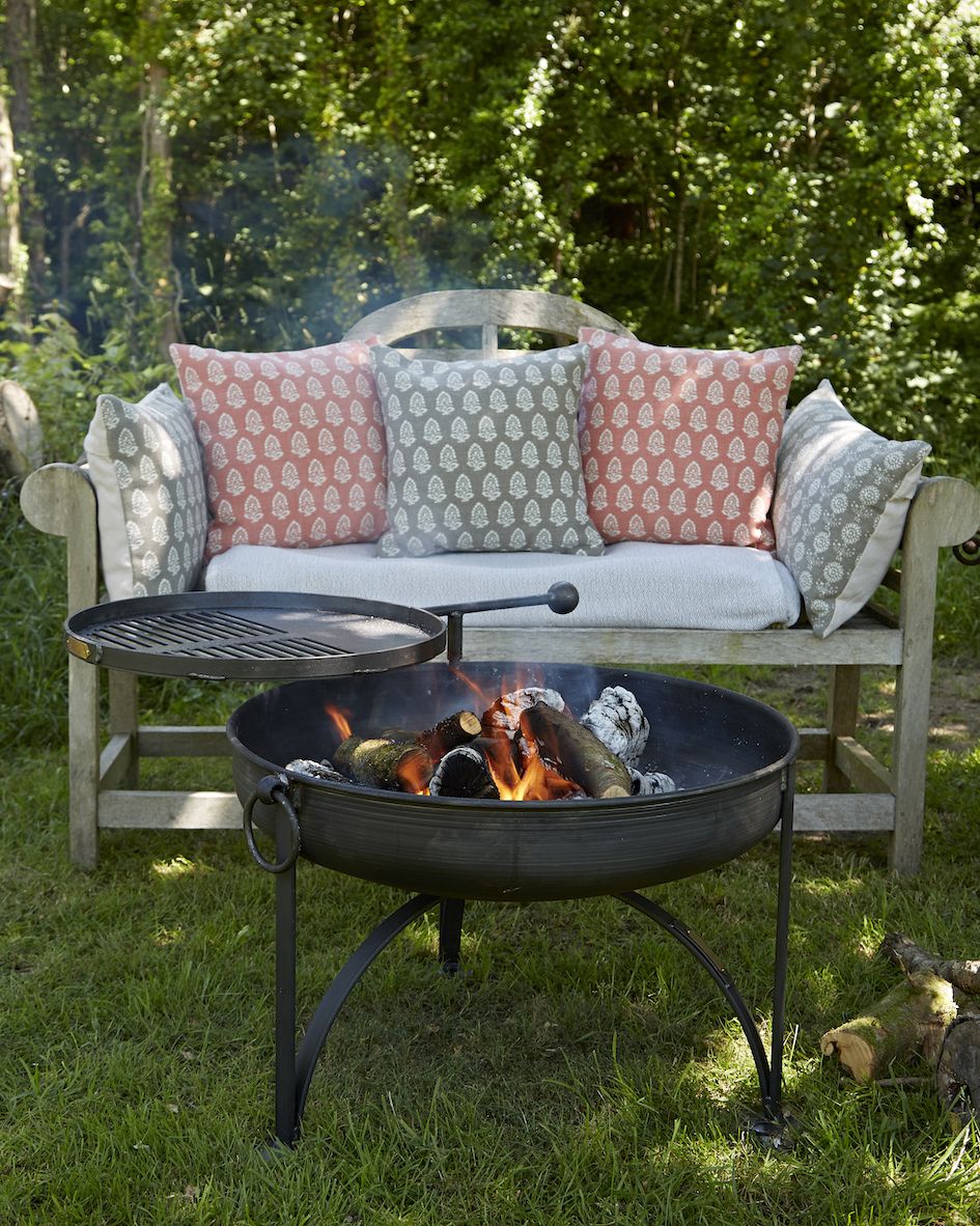 a grill with a fire pit and pillows on it