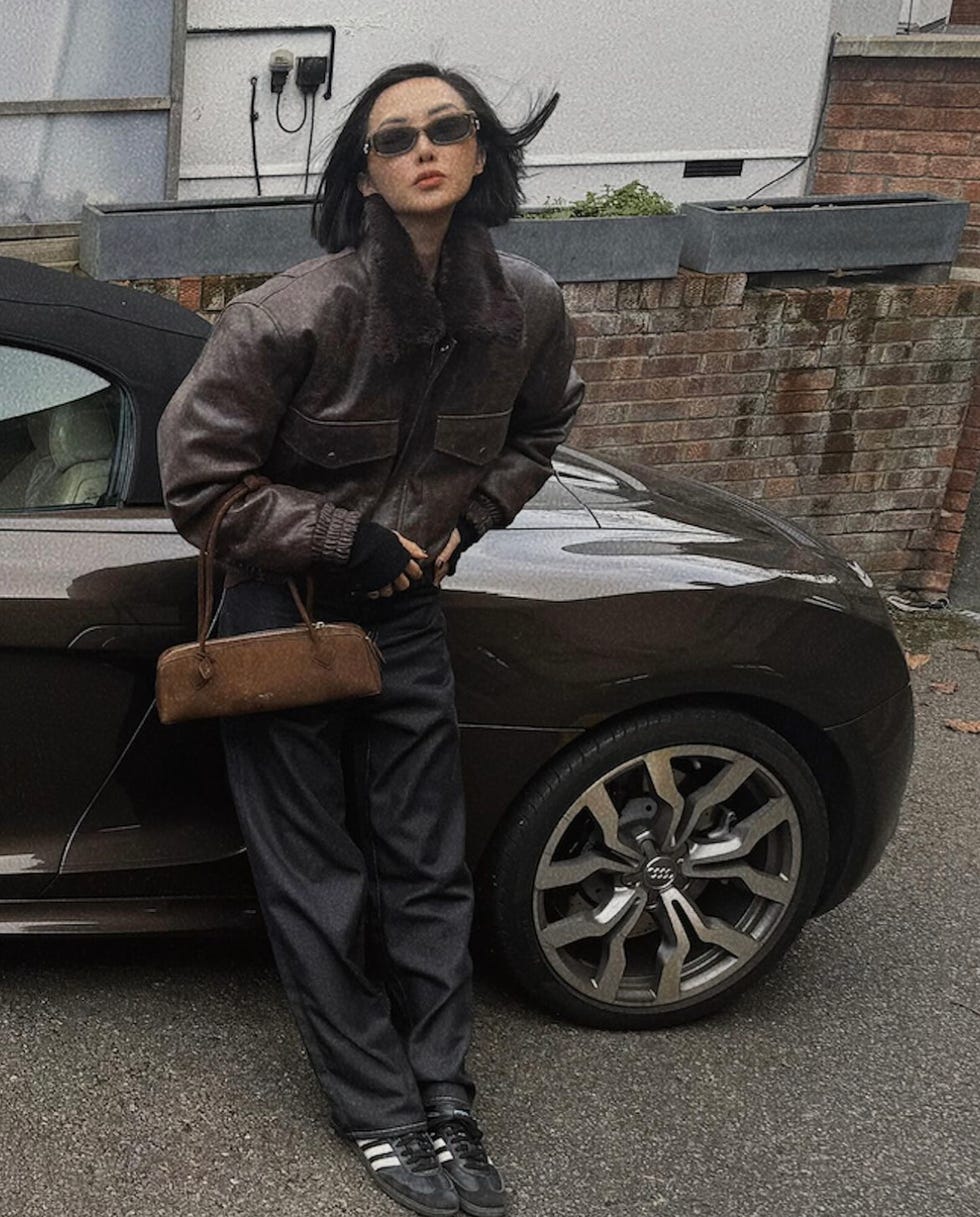 a person in a leather jacket leaning against a car