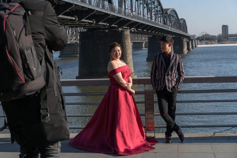 Bij de Vriendschapsbrug in de Chinese stad Dandong poseert een stel voor trouwfotos