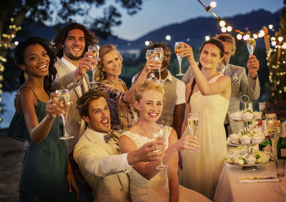 a bride and groom and wedding guests toasting champagne