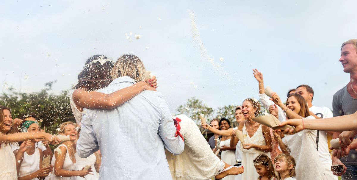 wedding guests tossing rice at newlyweds, outdoors
