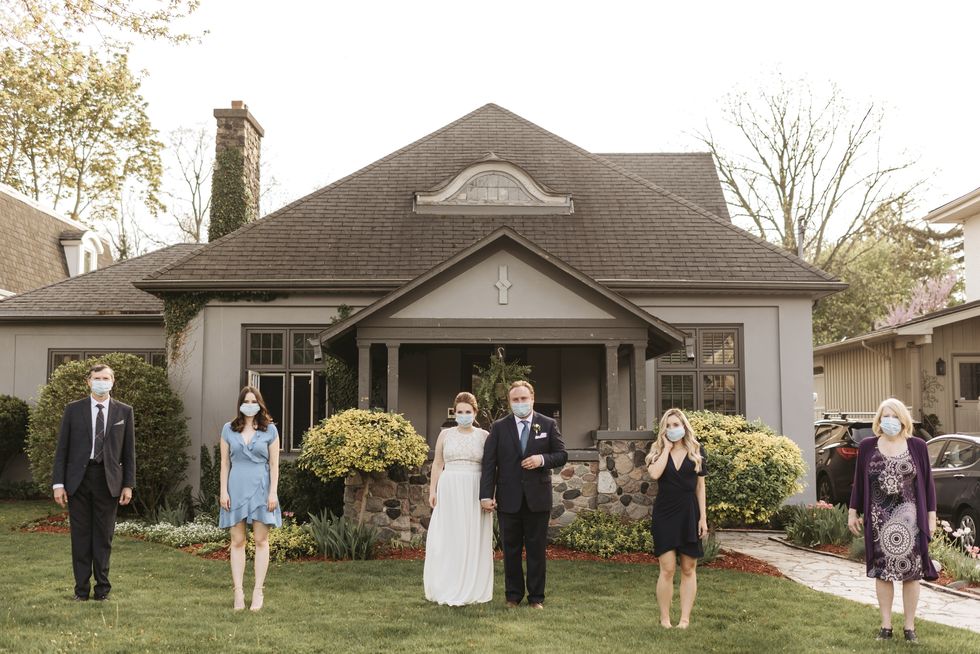 wedding party posing for group portrait on front lawn, wearing face masks during coronavirus crises