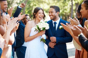 wedding guests clapping hands as a newlywed couple walk down the aisle