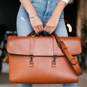 woman holding leather weekender bag