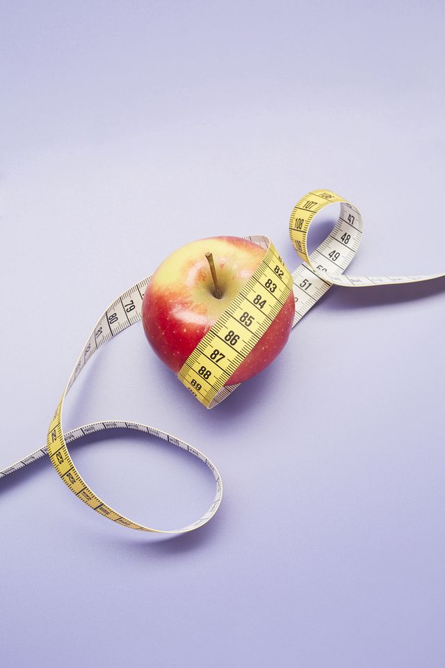 weight loss prevention high angle view of an apple and tape measure on purple background