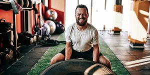 male athlete wincing with effort during truck tire gym workout