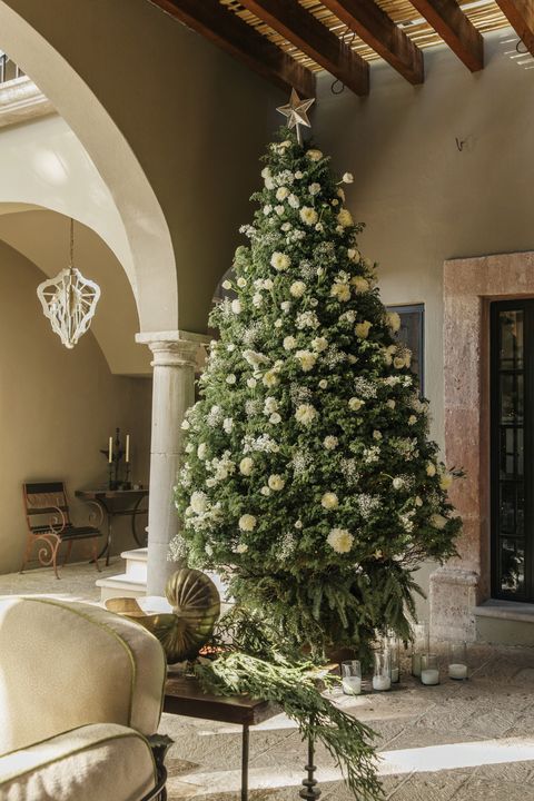 a towering cypress christmas tree in the breakfast room is decked in cut flowers and babys breath