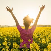 Mixed race African American girl female young woman athlete runner teenager in golden sunset or sunrise arms raised celebrating in field of yellow flowers mixed race african american girl female young woman athlete runner teenager in golden sunset or sunrise arms raised celebrating in field of yellow flowers