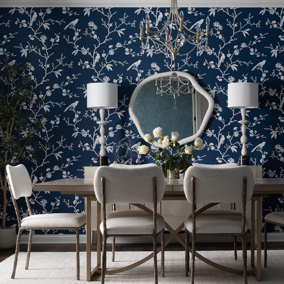 dining area with floral wallpaper a mirror and floral centerpiece