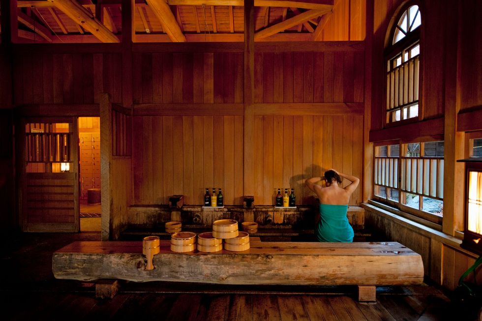 Aan baden in een onsen  hier in onsen Hoshi  gaat altijd een uitgebreide schrobbeurt vooraf Traditie wil dat je dat niet staand doet maar zittend op een krukje met houten lepels emmers en kommetjes Zeep en shampoo zijn voorhanden