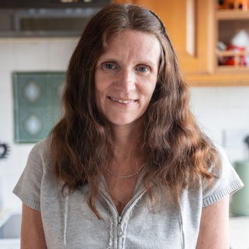 wendy, a white woman with long brown hair, standing in her kitchen and smiling