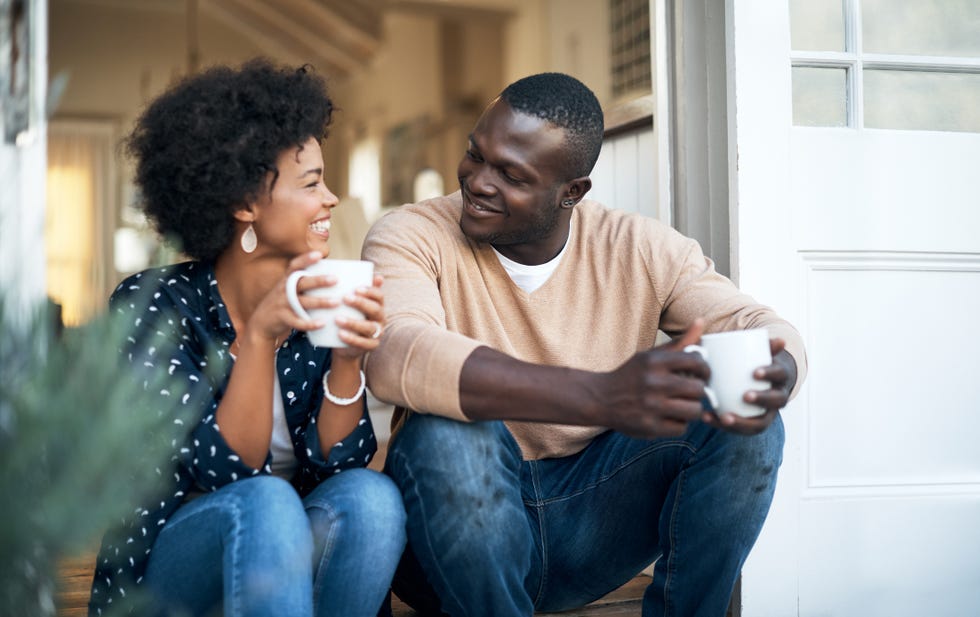 a couple holds coffee mugs and looks like they're having a happy but deep conversation